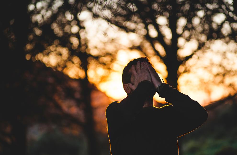 man face in hands sunset treets