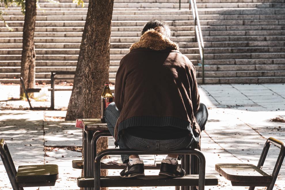 man from behind sitting on bench sidewalk