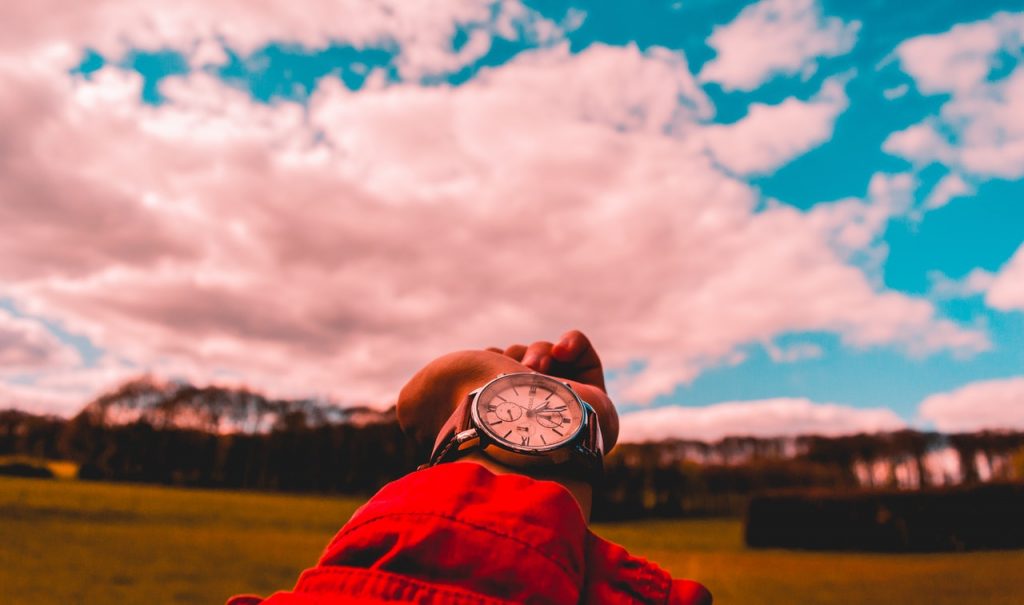 watch on wrist extended out with sky in background