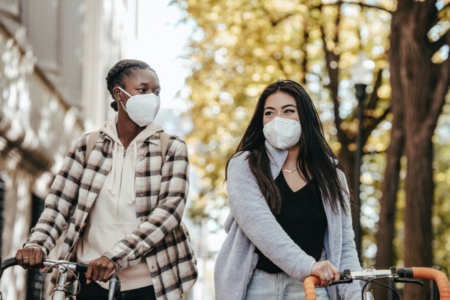 two women wearing face masks on bikes outside